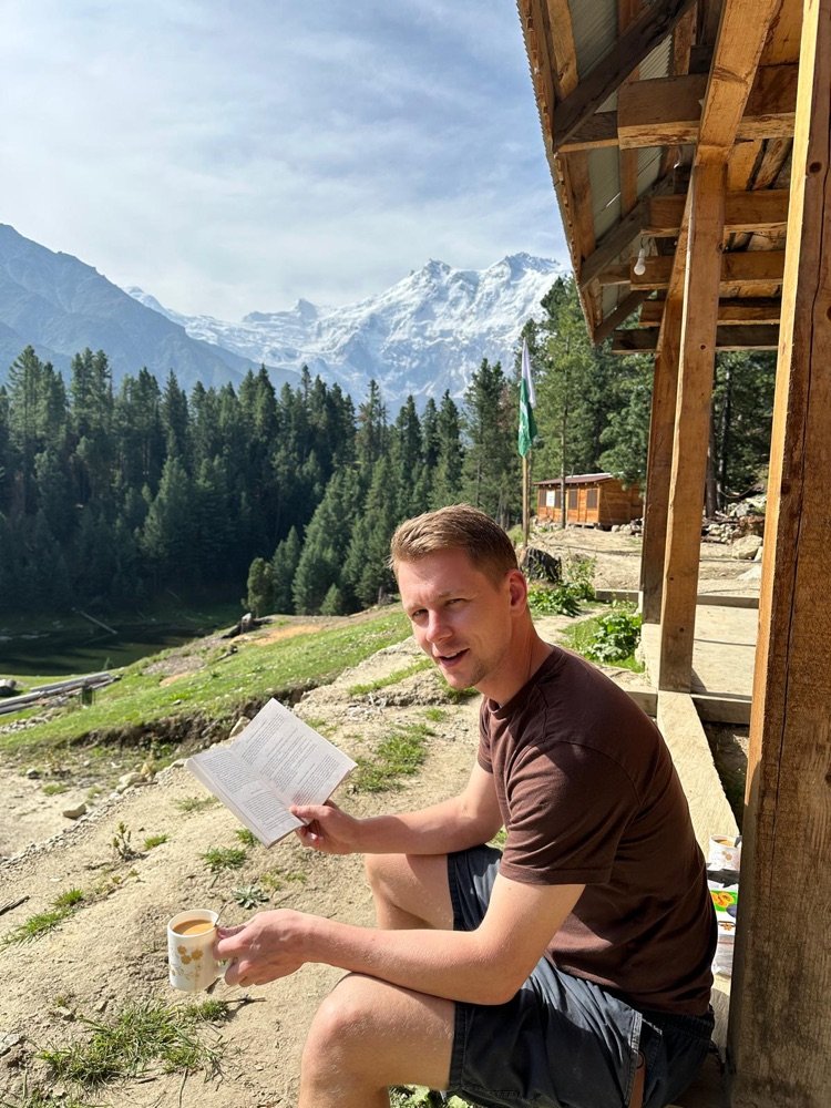 Nikolai Sie reading a book with the Himalayas behind him